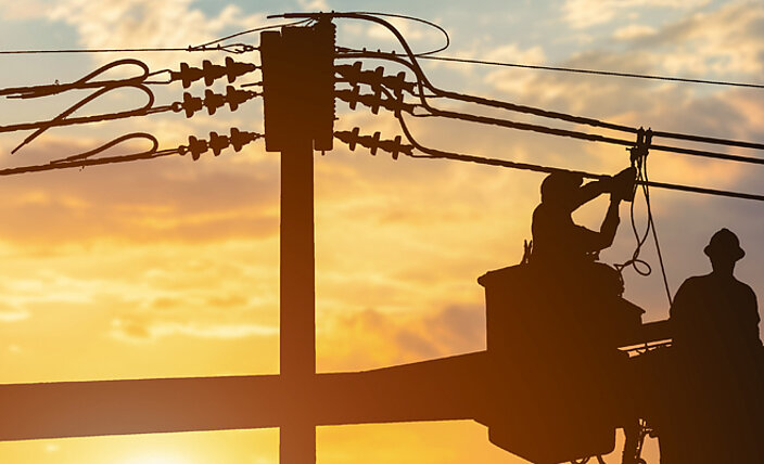 Schmuckbild - 2 Techniker arbeiten an Stromoberleitung im Sonnenaufgang